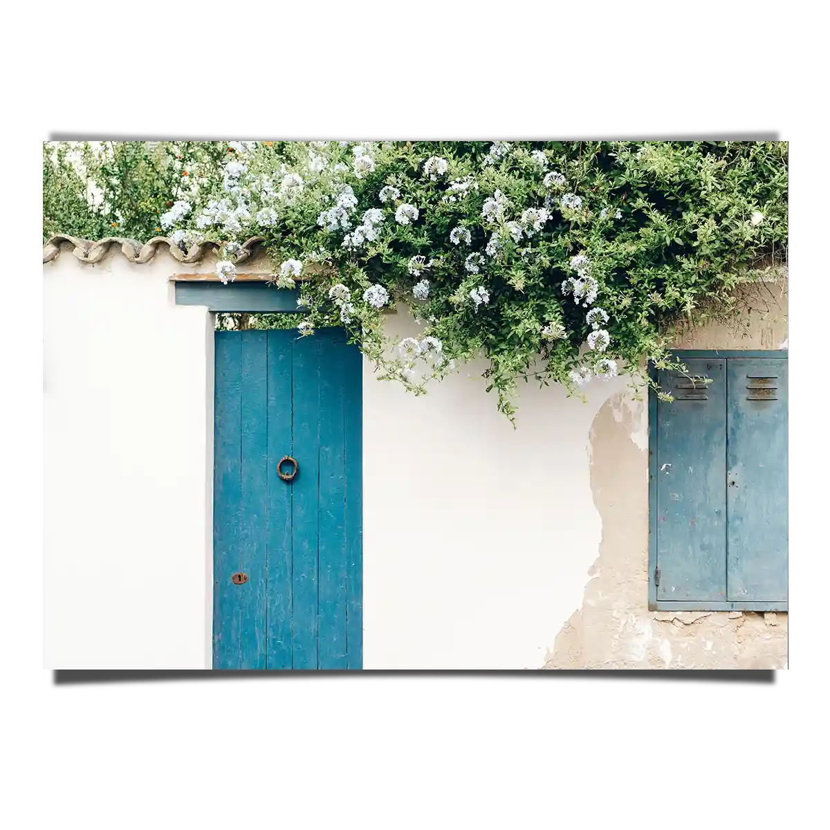 Traditional Greek House Facade with Blue Door and White Flowers in a Sunny Day